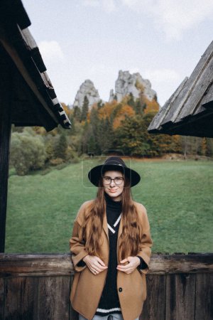 Foto de Mujer joven con chaqueta marrón y sombrero negro en el bosque - Imagen libre de derechos