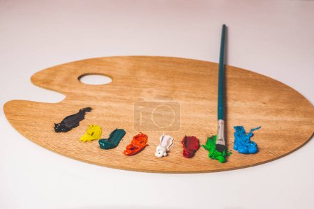 Foto de Wooden palette with colored oil paints and brushes isolated on a white background - Imagen libre de derechos