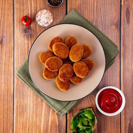 Foto de Chicken nuggets on a plate with sauce, wooden countertop - Imagen libre de derechos