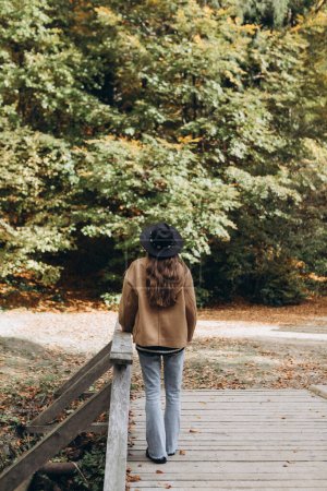 Photo for Young woman in a brown jacket and black hat in the forest - Royalty Free Image