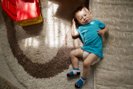 Foto de Niño está acostado en la alfombra cerca del colchón - Imagen libre de derechos
