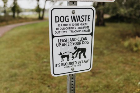 Foto de Close up image of dog waste sign along local walking trail - Imagen libre de derechos