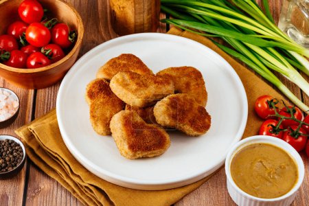 Foto de Nuggets de pollo frito en forma de corazón en un plato, salsa de mostaza al lado - Imagen libre de derechos