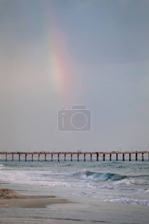 Foto de Rainbow over the pier on a stormy beach day in Oceanside - Imagen libre de derechos