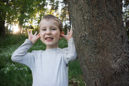 Foto de El niño se divierte cerca del árbol al aire libre. - Imagen libre de derechos