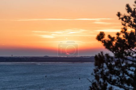 Téléchargez les photos : Bord rouge du soleil rayonnant hors de la brume pendant le coucher du soleil - en image libre de droit