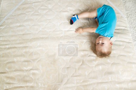 Foto de Bebé niño se encuentra en el colchón y mira a la cámara - Imagen libre de derechos