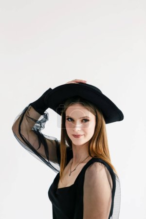 Téléchargez les photos : Portrait d'une femme en chemisier foncé et chapeau noir - en image libre de droit