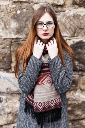 Téléchargez les photos : Jeune femme en lunettes portant un manteau enveloppé dans une écharpe - en image libre de droit