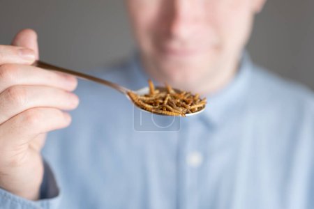 Photo for Meal worm foods.Laughing man with a spoon of worms. - Royalty Free Image