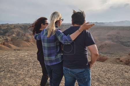 Foto de Tres personas mirando al Gran Cañón desde un mirador, ventoso - Imagen libre de derechos