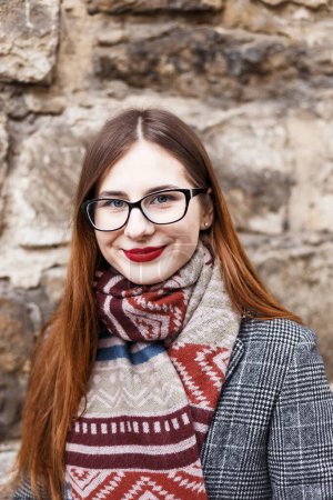 Photo for Young woman in glasses wearing a coat wrapped in a scarf - Royalty Free Image