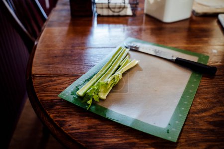 Photo for Bunch of Celery Piled on Cutting Board on Wood Kitchen Table - Royalty Free Image
