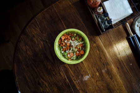 Téléchargez les photos : Bright Green Bowl of Chopped Vegetables on Dark Wood Kitchen Table - en image libre de droit