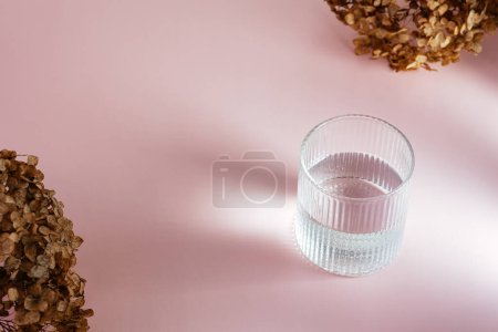 Téléchargez les photos : Un verre avec de l'eau sur la table. fond rose - en image libre de droit