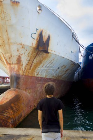 Foto de Joven macho mirando un gran barco en el puerto - Imagen libre de derechos