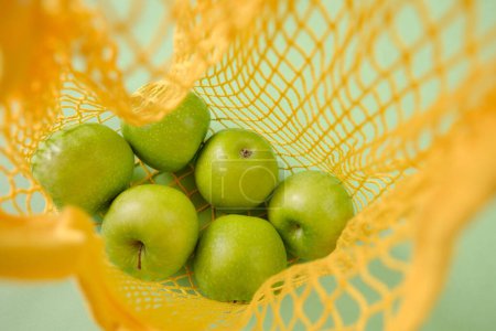Téléchargez les photos : Concept zéro déchet. Pommes vertes dans un sac en maillage.Consommation raisonnable - en image libre de droit