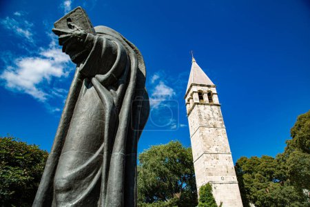 Téléchargez les photos : Bell tower and big bronze statue in park with blue sky - en image libre de droit