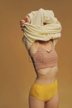 Photo for Young freckles woman take off a yellow sweatshirt - Royalty Free Image