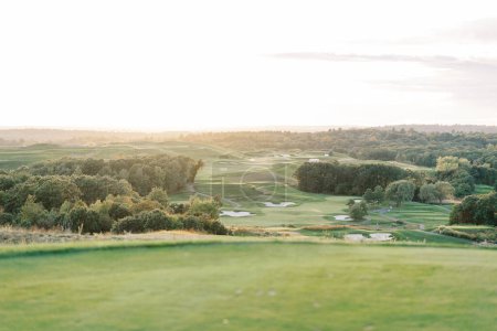 Téléchargez les photos : Golden sunset light over a well manicured lush green golf course - en image libre de droit