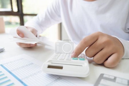 Photo for Hand of young asian business man working using calculator for planning accountant, graph for finance and report statistics, investment and profit of income, businessman analyzing with chart. - Royalty Free Image