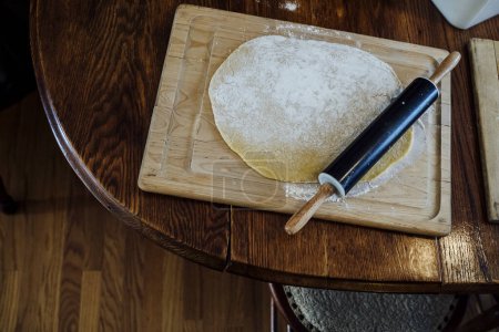 Téléchargez les photos : Black Rolling Pin Set on Pasta Dough on Wooden Cutting Board - en image libre de droit