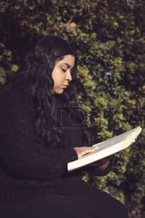 Foto de Joven, sentada leyendo un libro en el jardín - Imagen libre de derechos