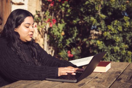 Téléchargez les photos : Femme latine avec de longs cheveux foncés, travaillant à l'extérieur avec ordinateur portable - en image libre de droit