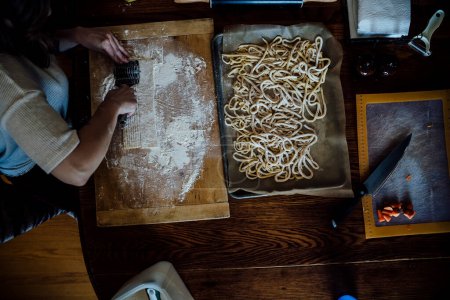 Téléchargez les photos : View from Above of Woman Cutting Homemade Pasta on Kitchen Table - en image libre de droit