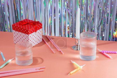 Foto de Ambiente festivo, caja de regalo, velas de pastel, tubos de cóctel, fondo brillante - Imagen libre de derechos