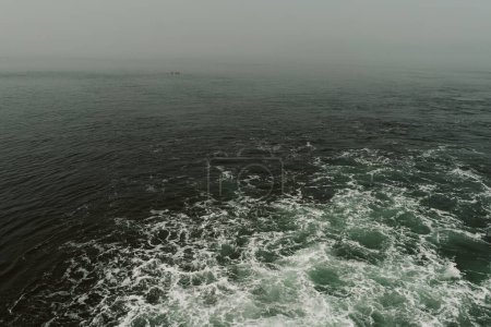 Téléchargez les photos : Backwash from a ferry boat with a fishing boat in the distance - en image libre de droit