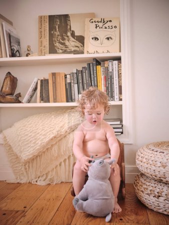 Foto de Un niño de pelo rizado juega con rinoceronte relleno en la sala de estar - Imagen libre de derechos