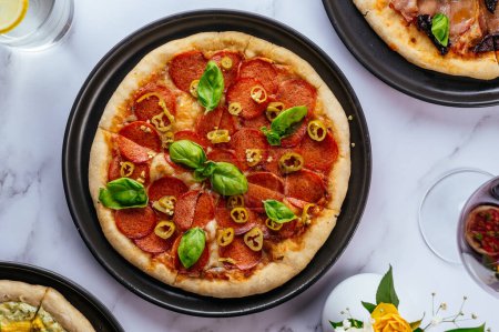 Foto de Homemade pizza with salami on a marble table - Imagen libre de derechos