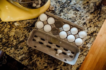 Foto de Carton of White Chicken Eggs on Granite Counter Next to Kitchen Mixer - Imagen libre de derechos