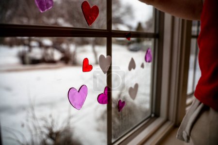 Foto de Rojo blanco y rosa corazón ventana aferramientos colocado en la ventana por niño - Imagen libre de derechos