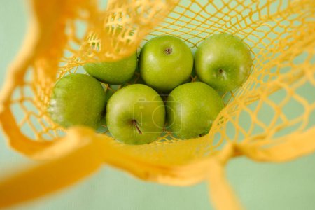 Foto de Zero waste concept. Green apples in a yellow mesh bag close-up - Imagen libre de derechos