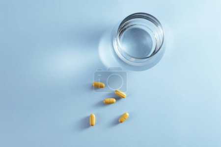 Photo for Vitamins in tablets on the table and a glass of water next to it. - Royalty Free Image