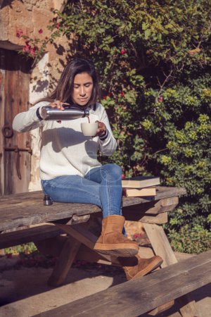 Foto de Hermosa mujer latina vierte una taza de café, en el campo - Imagen libre de derechos