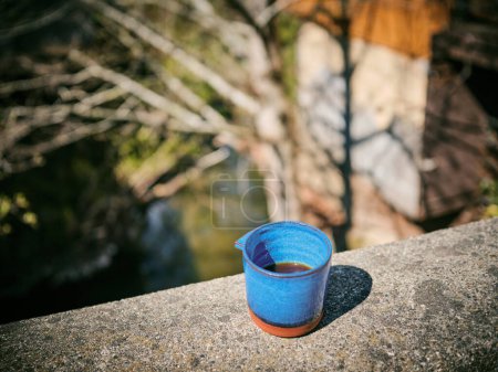 Foto de Half full blue ceramic coffee mug with unique handle outside on ledge - Imagen libre de derechos