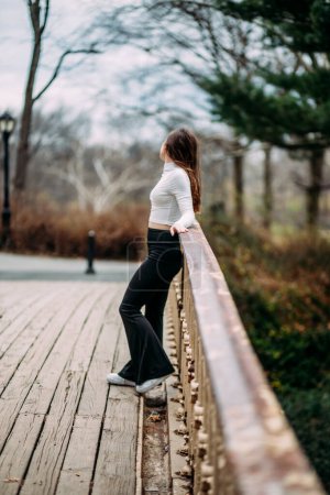 Téléchargez les photos : Adolescent fille debout sur pont regarder loin - en image libre de droit
