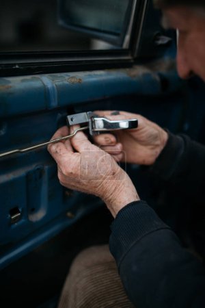 Téléchargez les photos : Le vieux technicien installant la porte de voiture à la maison gros plan - en image libre de droit