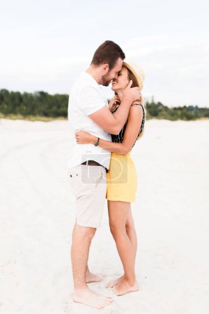 man and a woman are hugging on a sandy beach in summer