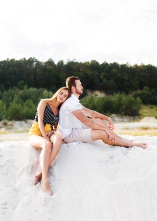 Téléchargez les photos : Young couple in love are sitting on a sandy beach on vacation - en image libre de droit