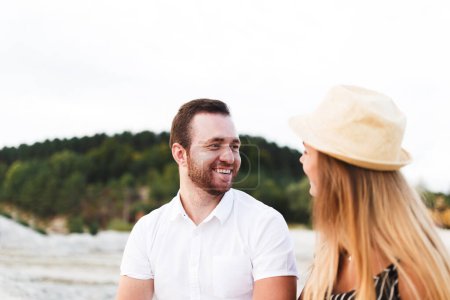 Téléchargez les photos : Man and a woman in light clothes are laughing together on the beach - en image libre de droit