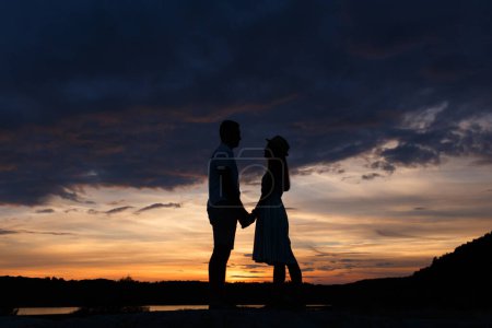 Téléchargez les photos : Couple standing holding hands at summer sunset - en image libre de droit