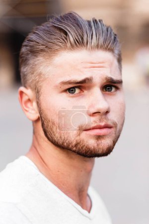 Jeune homme blond barbu en t-shirt dans la rue de la ville d'été