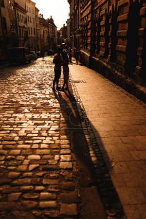 Foto de Man and  young woman embrace in rays of setting sun in the city - Imagen libre de derechos