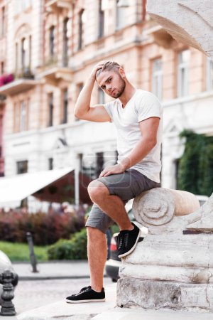 Photo for Bearded blond man in a t-shirt and shorts on street of summer city - Royalty Free Image