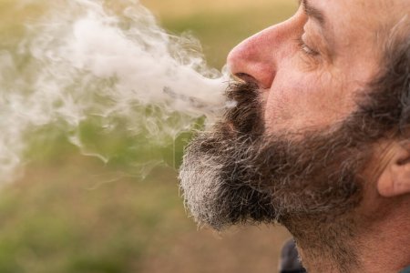 Foto de Hombre de perfil fumando marihuana y soplando humo - Imagen libre de derechos