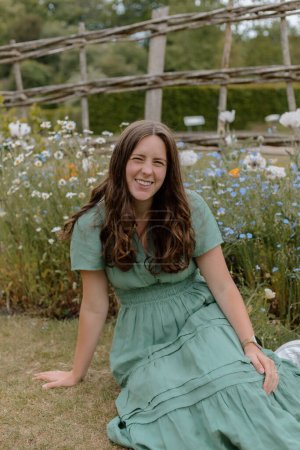 Téléchargez les photos : Fille en robe verte assis dans un jardin anglais au printemps - en image libre de droit